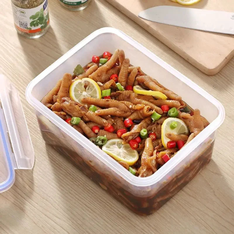 Kühlschrank Aufbewahrungsbox mit Deckel, gefüllt mit marinierten Lebensmitteln und frischen Zutaten auf einem Tisch.